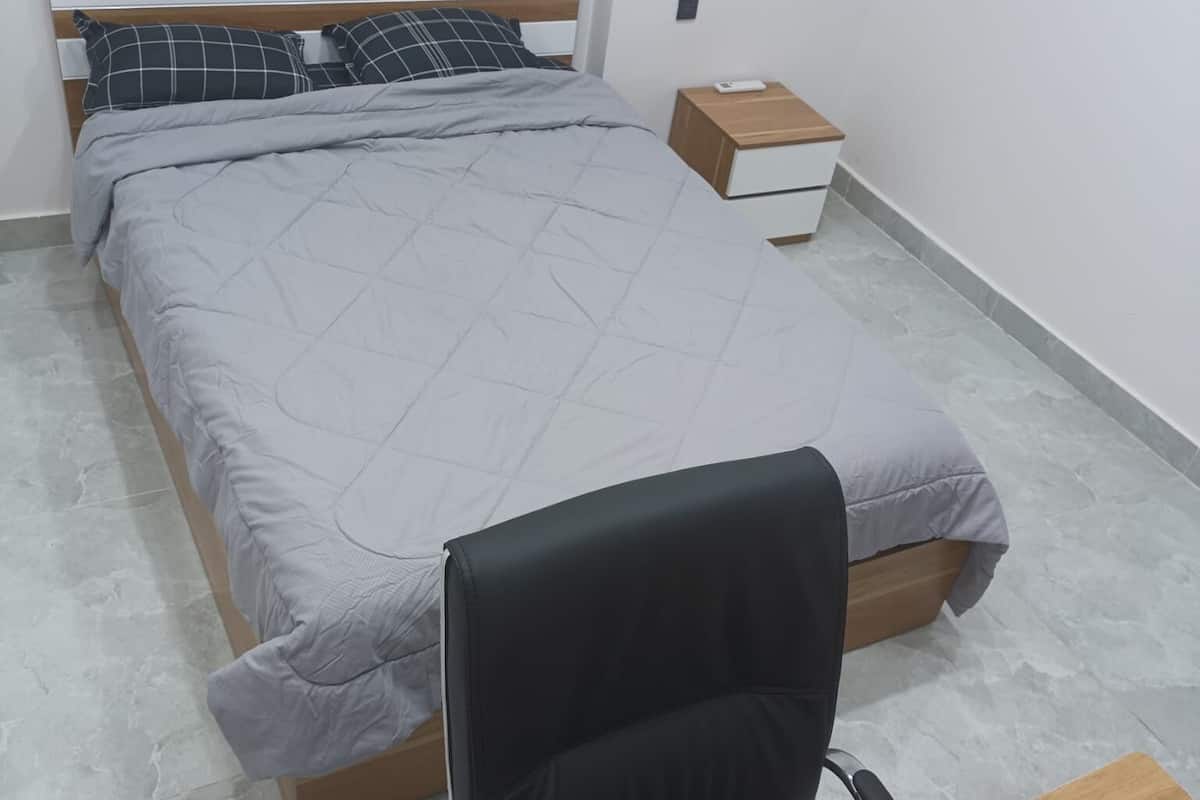 Un dormitorio con una cama, una mesita de noche, un escritorio y una silla.