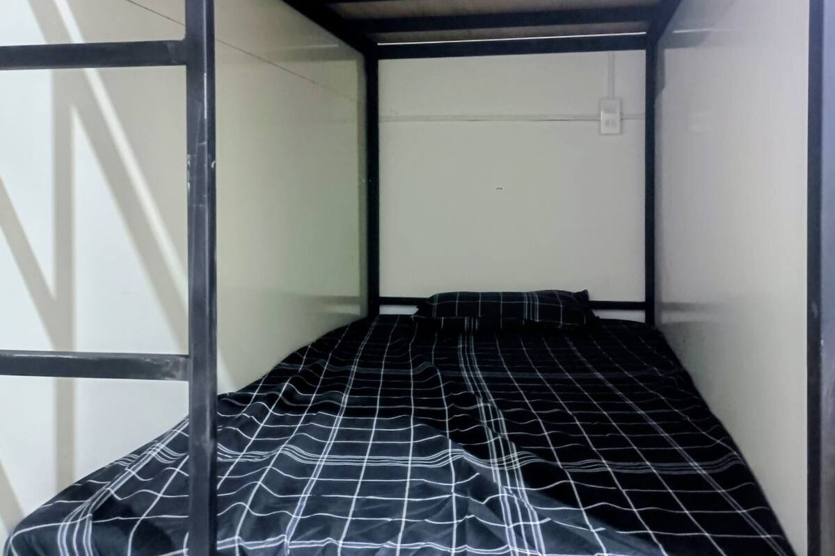 A bunk bed with a black and white checkered bedspread, wooden headboard, and metal frame.