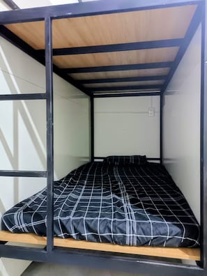 A bunk bed with a black and white checkered bedspread, wooden headboard, and metal frame. - WeDiscover Da Nang CoLiving & CoWorking (Ngu Hanh Son)