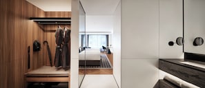 Una habitación de hotel moderna con un armario de madera, una cama, una mesita y vistas a la ciudad.