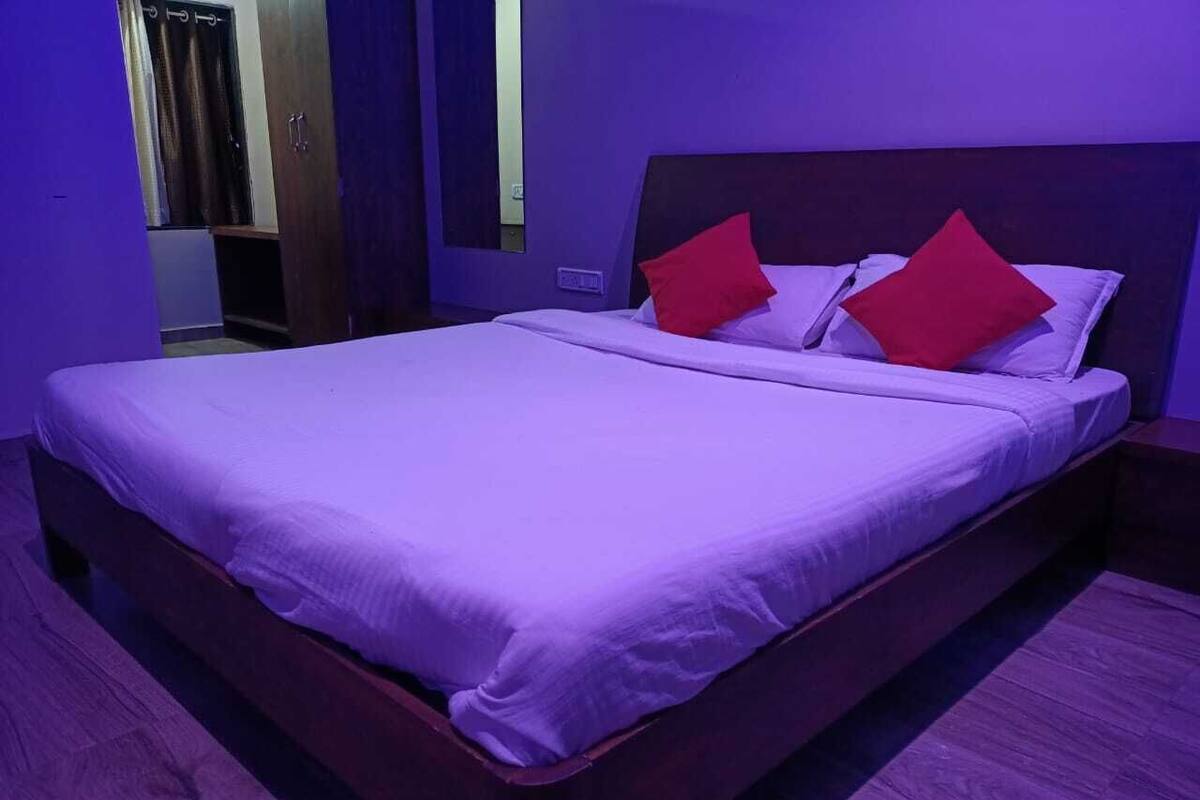 A bed with a wooden frame, a headboard, and red pillows.