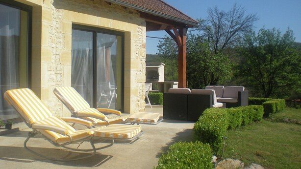 A stone building with a patio area featuring lounge chairs and a seating area. - Holiday Home in Montcléra with Barbecue (Montclera)