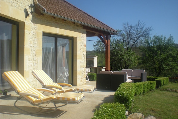 Ein Steinhaus mit einer Terrasse, die Lounge-Stühle und eine Sitzecke bietet.