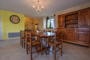 Ein Essbereich mit Holztisch und Stühlen, einer Chandelieber und einer Uhr an der Wand.