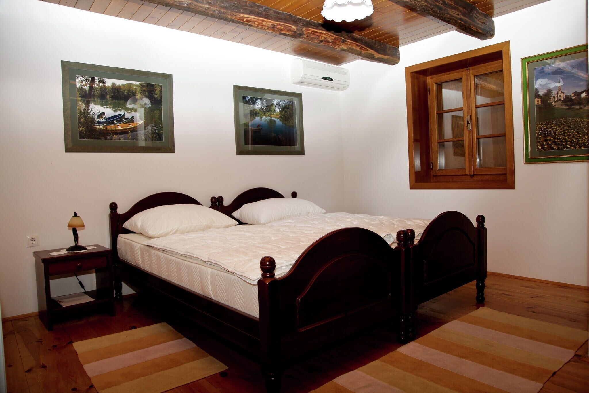 A bedroom with a wooden bed, a nightstand, a lamp, and framed pictures on the wall.