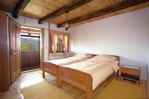 Una cama de madera con cabecera, una mesita de noche, una ventana con cortinas y vistas al exterior.