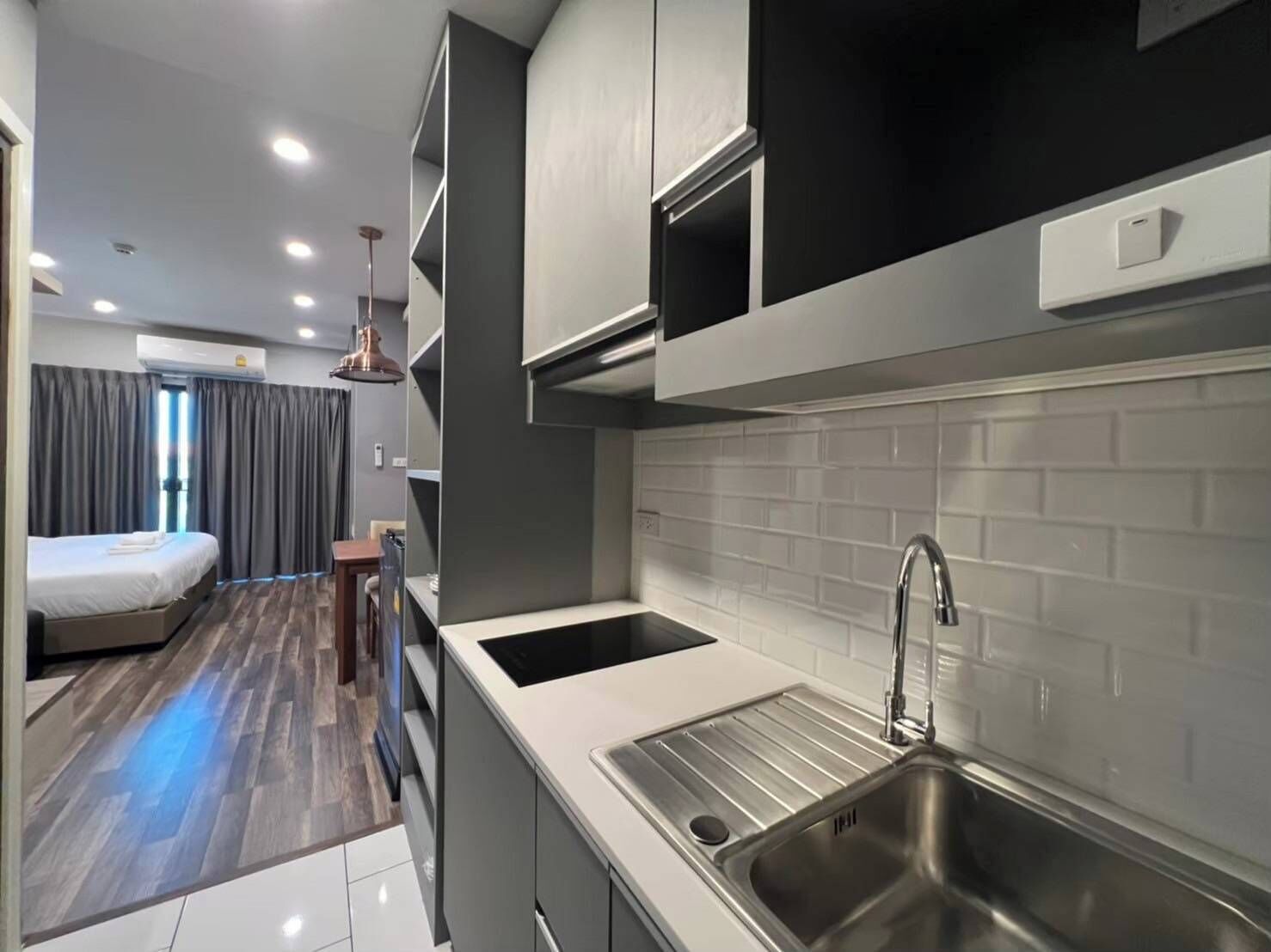 Cocina compacta con lavamanos, armarios y comedor con cama.