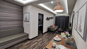 Een moderne woonkamer met een eethoek, een bank, een salontafel en een hanglamp.