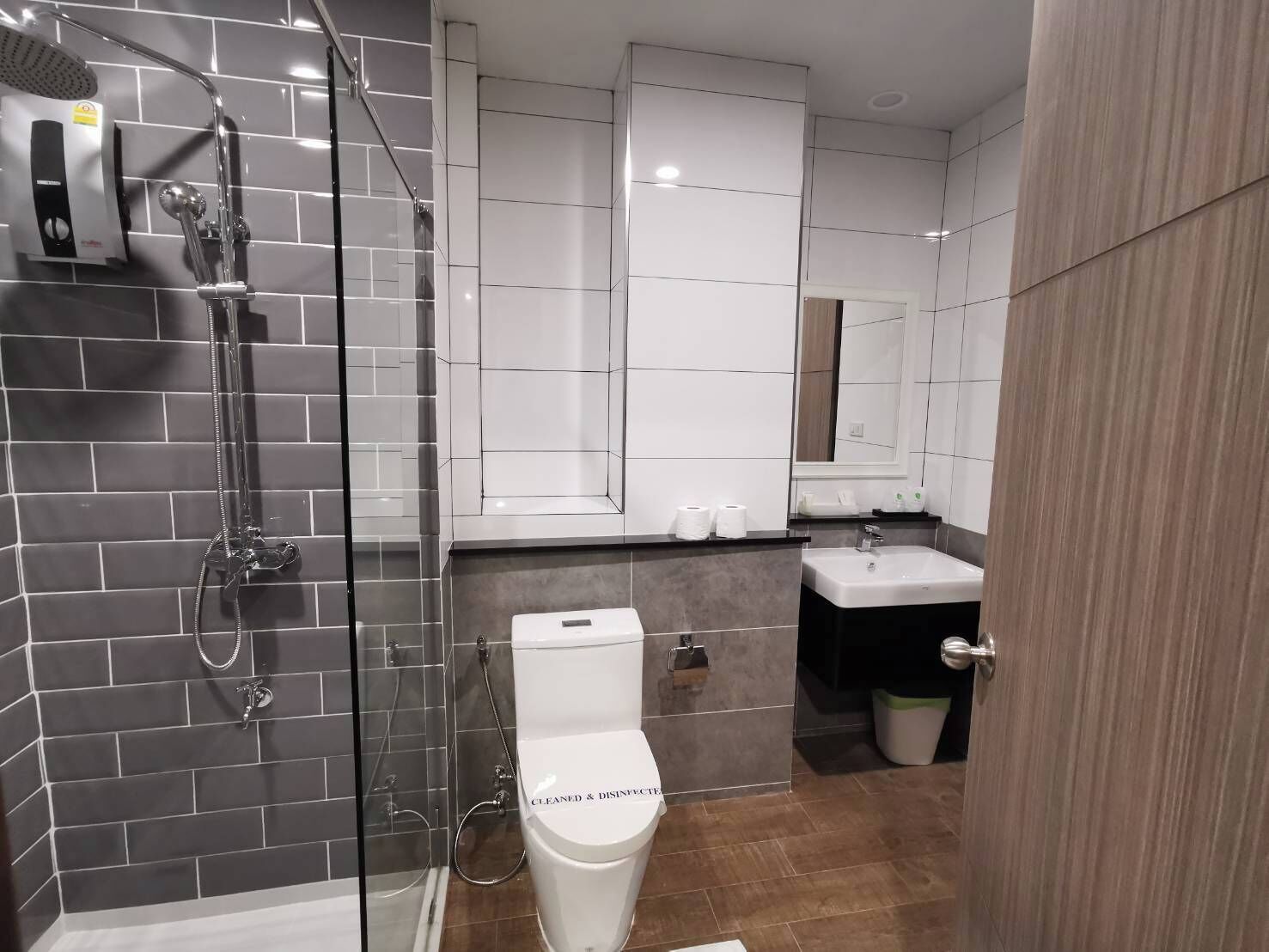 Un baño moderno con ducha envuelta en vidrio, un inodoro blanco y un lavabo con un espejo arriba.