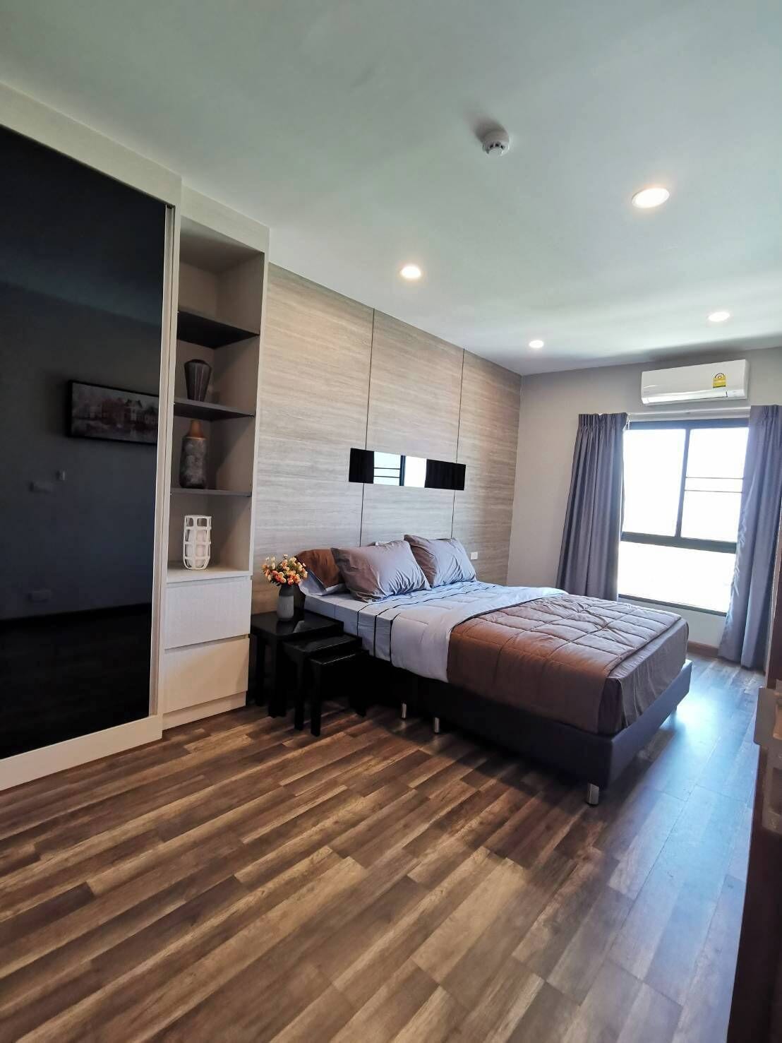 Ein modernes Schlafzimmer mit Bett, Einbauschrank, Nachttischen und einem Fenster mit Vorhängen.