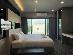 Ein modernes Hotelzimmer mit einem großen Bett, einem Schreibtisch und einem Balkon mit Blick.
