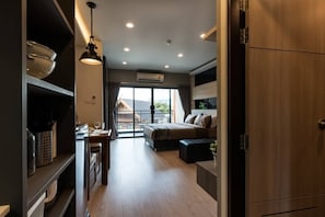 A modern interior with a kitchen area, a dining table, a sofa, and a large window with a view. - Premire Luxe Hotel Chonburi (Chonburi)