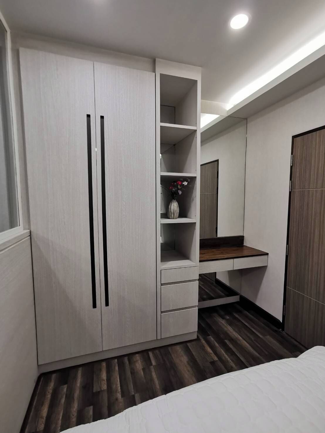 Un dormitorio con un armario, una tocador con espejo y una cama.