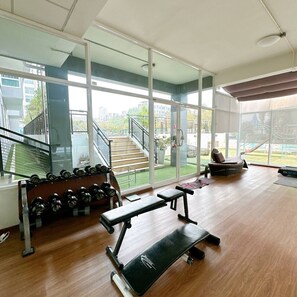 Una palestra con panche, manubri e una scala che conduce a una zona esterna.