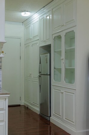 A kitchen with white cabinetry, a stainless steel refrigerator, and a wooden floor. - Mid century style near Nimman and Maya (Tambon Chang Phueak)