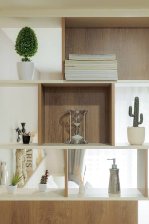 A shelf with a potted plant, a stack of papers, a cactus, a decorative hourglass, and a small vase with a pump bottle. - Stay Classy – Pool• Gym• Balcony (Chiang Mai)