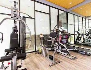 Ett gym med konditionsmaskiner, styrketräningsutrustning och ett löpband.