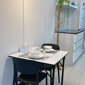 Un coin repas avec une table blanche, des chaises noires et une petite plante en pot.