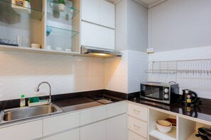 Une cuisine compacte équipée d’un évier, d’une cuisinière, d’un four à micro-ondes et d  ’une bouilloire.