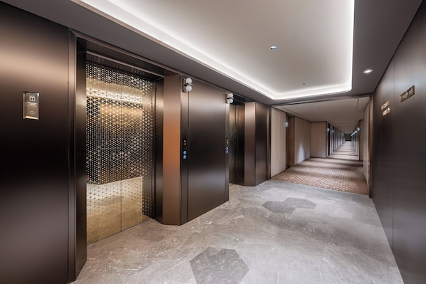 A modern elevator with a metallic finish and a patterned glass door.