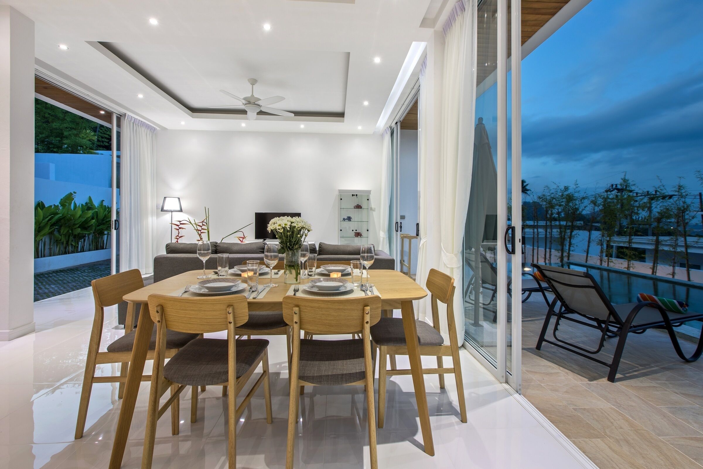 A modern dining area with a table set for four, a sofa, and a balcony with outdoor seating.