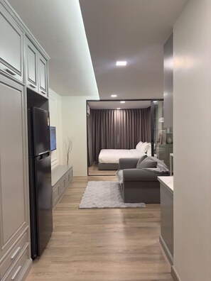 Ein modernes Hotelzimmer mit einer Küchenzeile, einem Bett, einer Sitzecke und Blick auf die Stadt.