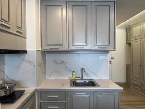 Una cocina moderna con encimeras de mármol, un lavamanos de acero inoxidable y armarios grises.