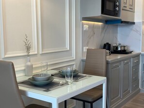 Una cocina moderna con una mesa de comedor blanca preparada para dos personas, un microondas y una cafetera.