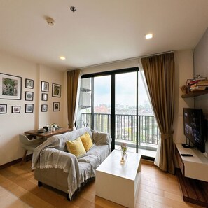 Una sala de estar moderna con un sofá, una mesa de centro, un televisor y un balcón con vistas.