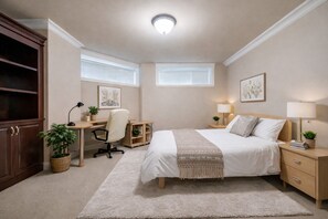 Ein Schlafzimmer mit Bett, Schreibtisch, Stuhl, Nachttischen und einem Kleiderschrank.