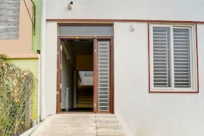 A residential entrance with a sliding door, a small staircase, and a window with blinds.