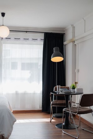 Una camera moderna con un tavolo da pranzo, sedie, una lampada da terra e un letto.