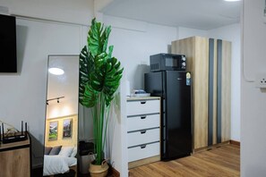 Una cocina compacta con refrigerador, microondas y un mueble de madera.