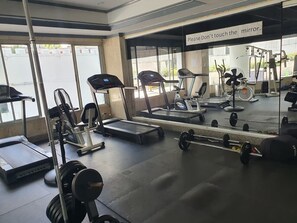 Un gimnasio con cintas de correr, máquinas de pesas y un espejo.