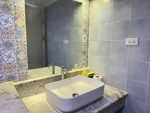 Un bagno con un lavandino bianco, uno specchio e una doccia.
