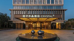 A modern hotel entrance with a sign reading 'Crystal Hotel,' a glass facade, and a water feature in front. - Crystal Hotel Qingdao Hi-Tech Convention (Qingdao)