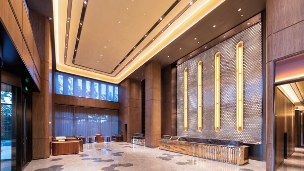 A spacious lobby with a reception desk, seating areas, and a large wall with vertical light fixtures. - Crystal Hotel Qingdao Hi-Tech Convention (Qingdao)