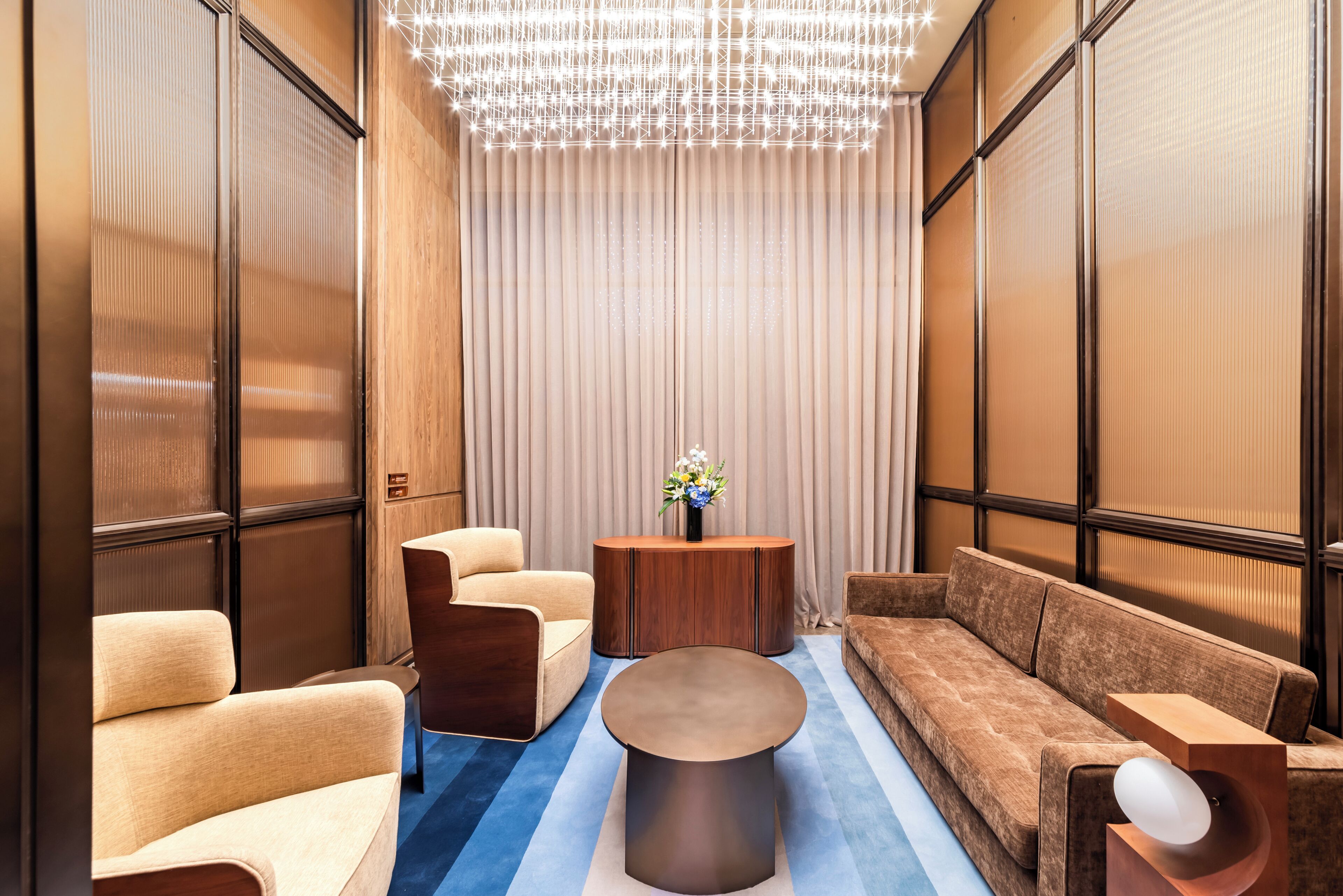 A modern interior with a sofa, armchairs, a round coffee table, and a decorative vase.