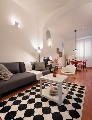 Een moderne woonkamer met een bank, salontafel en een eethoek met stoelen.
