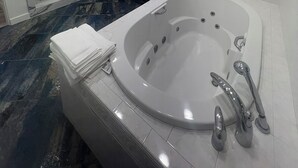 Een moderne badkamer met een ruime badkuip, een douchecabine met glazen wanden en een wastafel met spiegel.