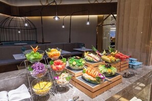 A buffet with various dishes and a seating area with tables and chairs. - Crystal Hotel Qingdao Jimo Ancient City (Qingdao)