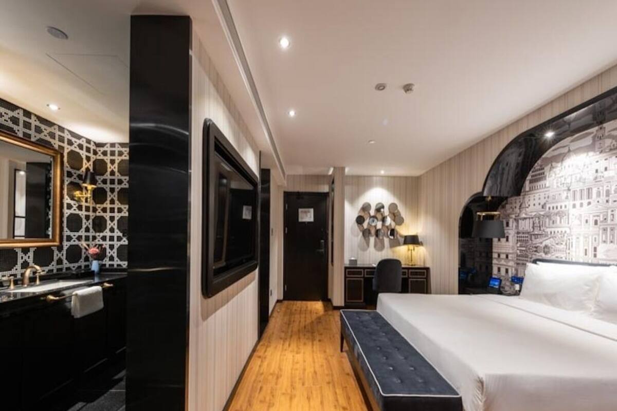 A hotel room with a large bed, a TV, a desk, and a mirror.