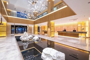 A modern hotel lobby with a reception desk, seating area, and a central water feature. - Crystal Hotel Qingdao Jimo Ancient City (Qingdao)