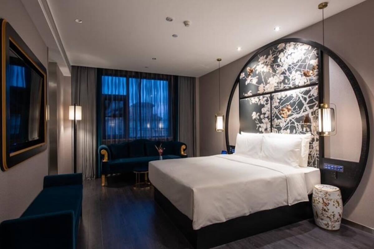 A modern hotel room with a large bed, a seating area, and a decorative wall.