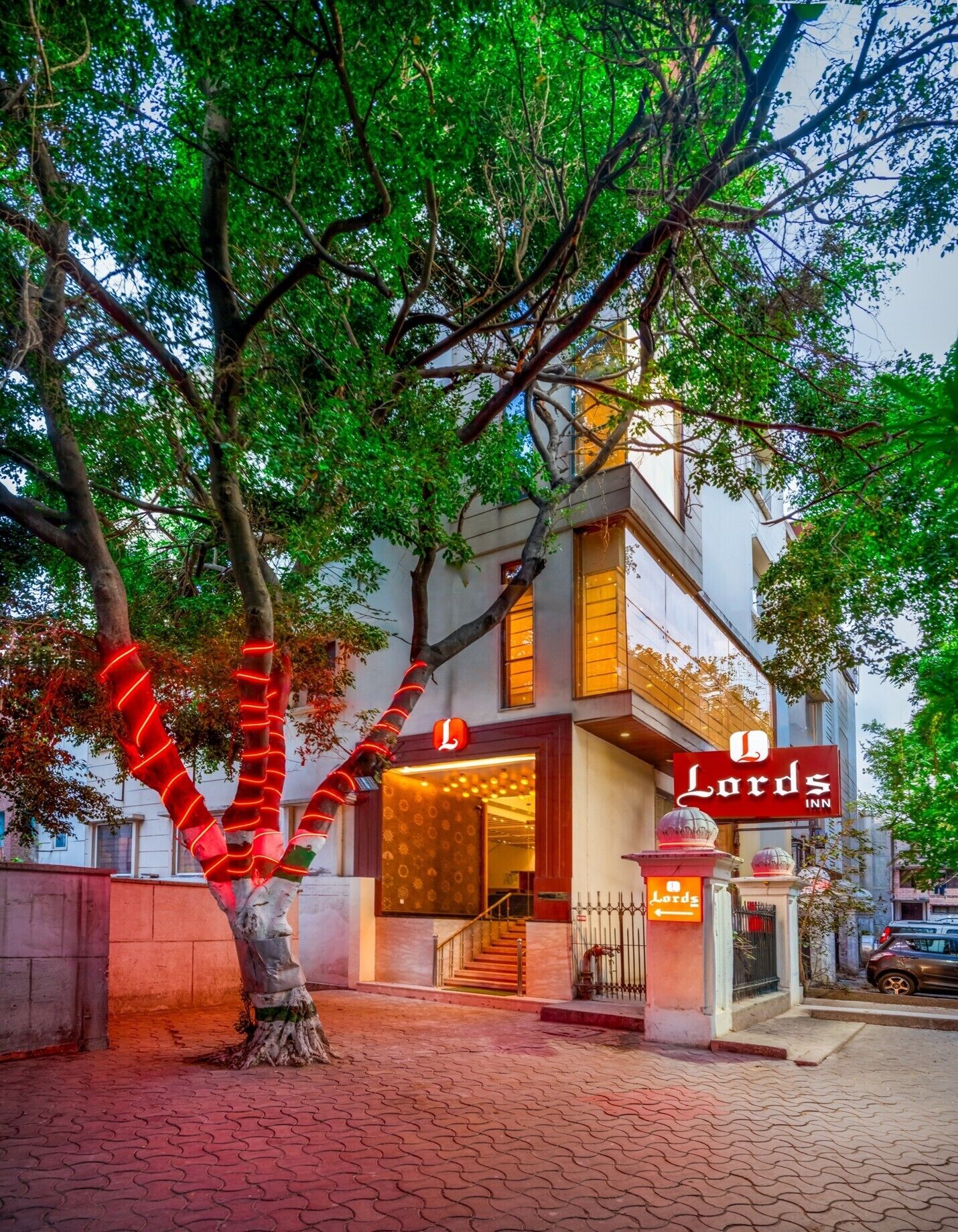 A hotel with a prominent sign, a staircase leading to the entrance, and a tree with red lights.