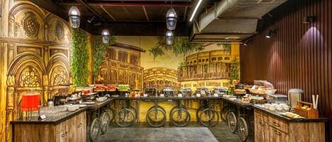 A restaurant with a central bar area, decorative wall murals, and a variety of food and drink items displayed on the counter.