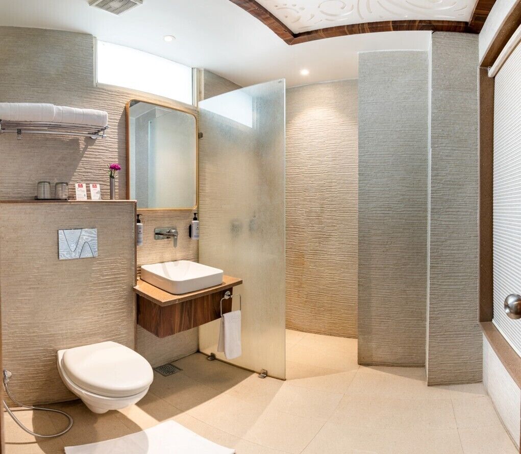 A modern bathroom with a toilet, sink, mirror, and shower.