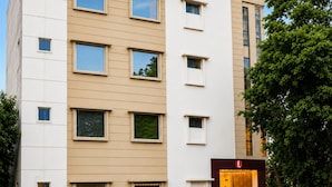 Um hotel de vários andares com design moderno, apresentando um logotipo em destaque no topo e uma entrada bem iluminada.
