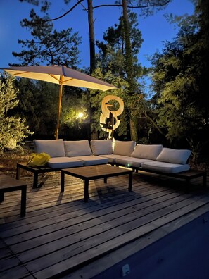Eine Terrasse im Freien mit einer Eckcouch, einem Couchtisch und einem großen Sonnenschirm.