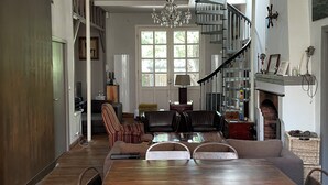 A spacious dining area with a long wooden table, a chandelier, and a spiral staircase. - Family villa with pool and outbuilding, very large grounds (Cap Ferret)